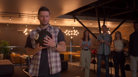 a portrait of a caucasian man throws a bowling ball and knocks out a shot with one throw. multi-ethnic group of friends bowling