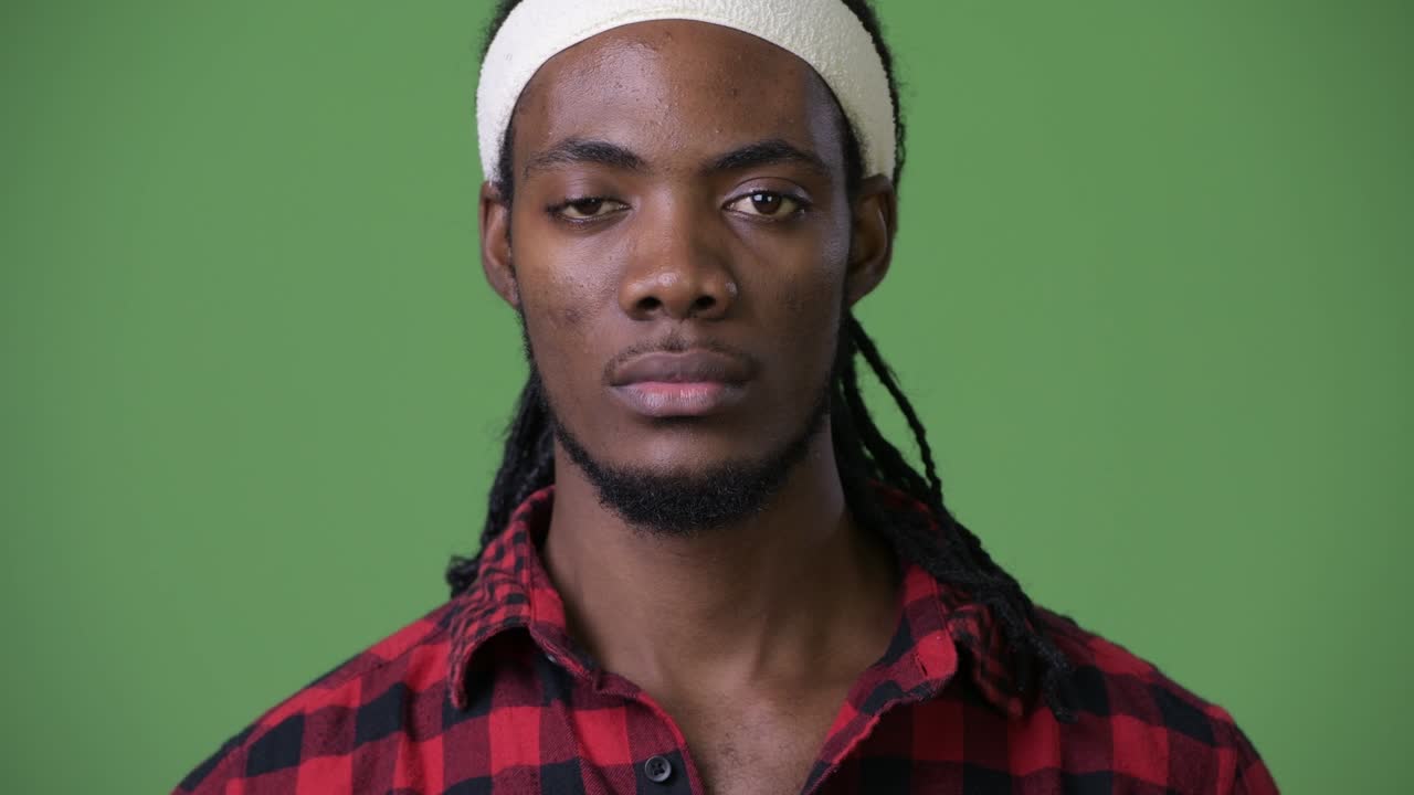 joven hombre africano guapo con dreadlocks contra un fondo verde