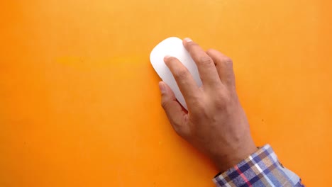 persona que usa un ratón de computadora blanco en una superficie naranja