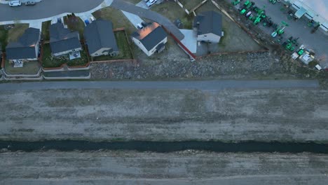 Top-down-drone-shot-of-a-small-irrigation-creek-running-past-a-neighborhood's-outer-perimeter