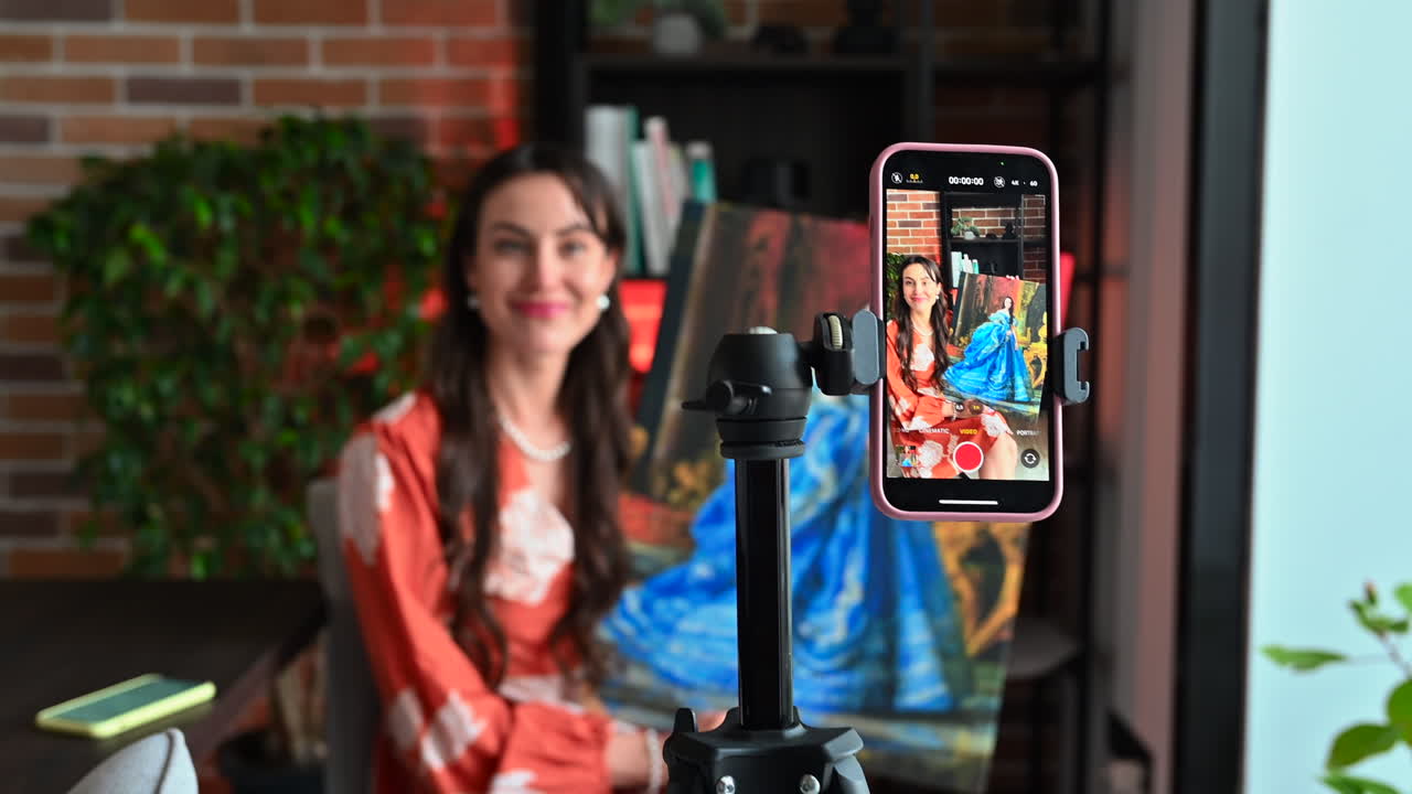 CHISINAU - MOLDAVIA, 06 GIUGNO 2023: influencer in abito rosso realizza un vlog con iPhone 14 presentando un selfie dipinto