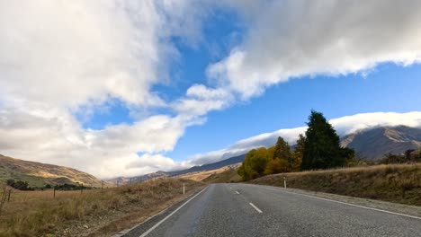 a serene drive along a winding road in wanaka, new zealand, showcasing vibrant autumn foliage and expansive skies