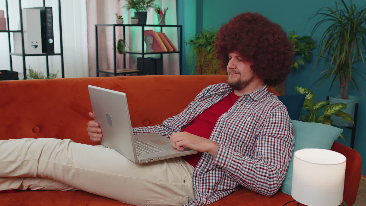 Young man freelancer lying on couch closing laptop pc after finishing work in living room at home