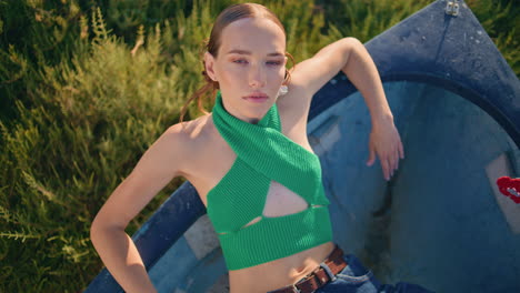 una mujer de moda modelando un barco en un prado verde en primer plano. una chica atractiva descansando