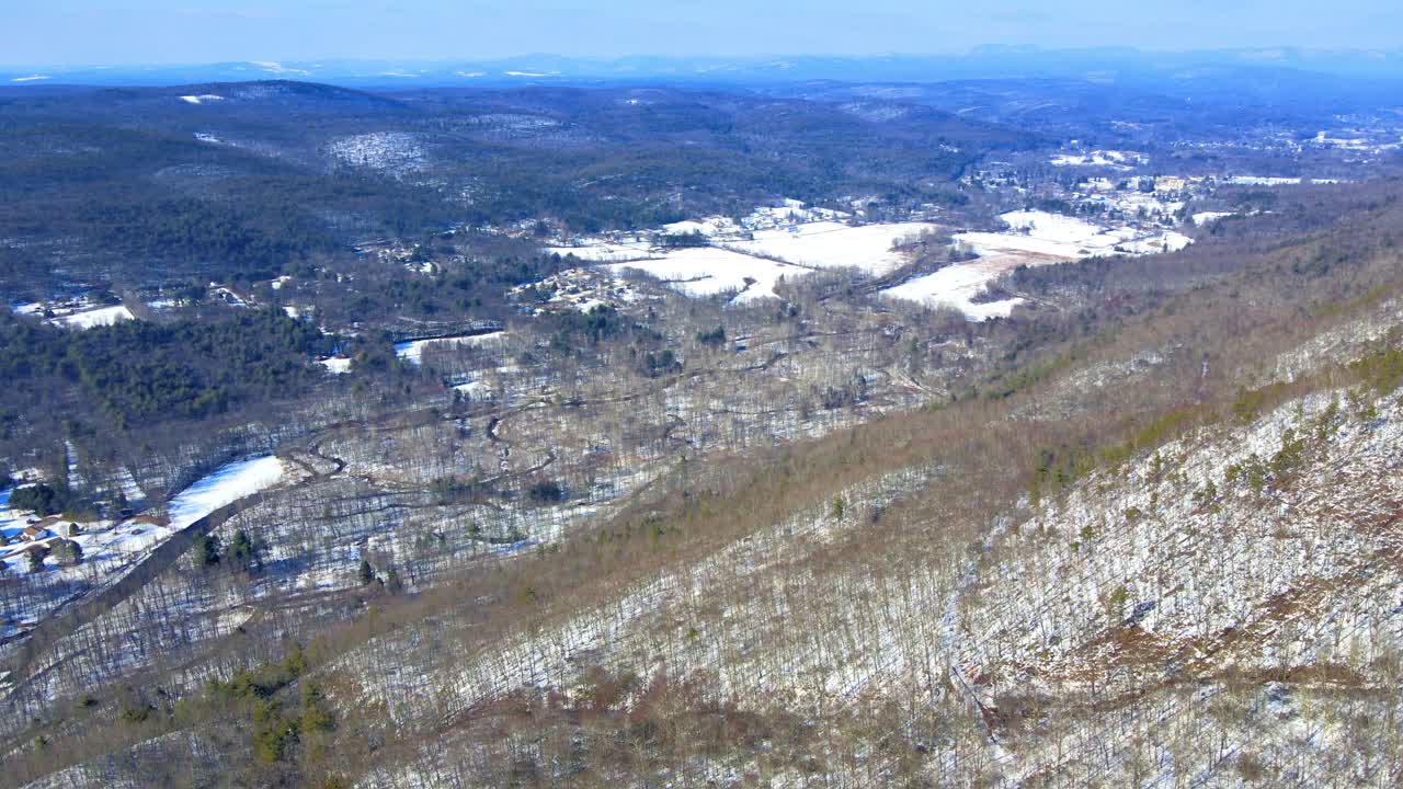 Aerial drone video footage of a snowy mountain valley during early spring with sunny blue skies