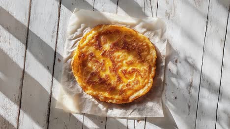 close-up of a golden brown omelette on a white wooden surface