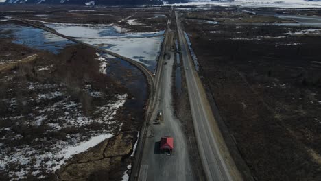 4k-Drone-over-highway-slowly-panning-up-revealing-large-whitecapped-mountains-with-blue-skies-and-patches-of-white-clouds-in-the-sky,-Alaska