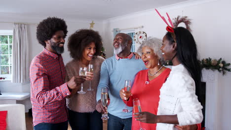 Portrait-Of-Parents-With-Adult-Offspring-Making-A-Toast-With-Champagne-As-They-Celebrate-Christmas-Together