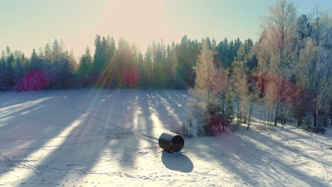 Wooden-Barrel-Sauna-And-A-Cabin-On-Snowy-Landscape-During-Snowfall-In-Winter