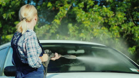a woman washing my car in the backyard of her house on the background of the doors to the garage