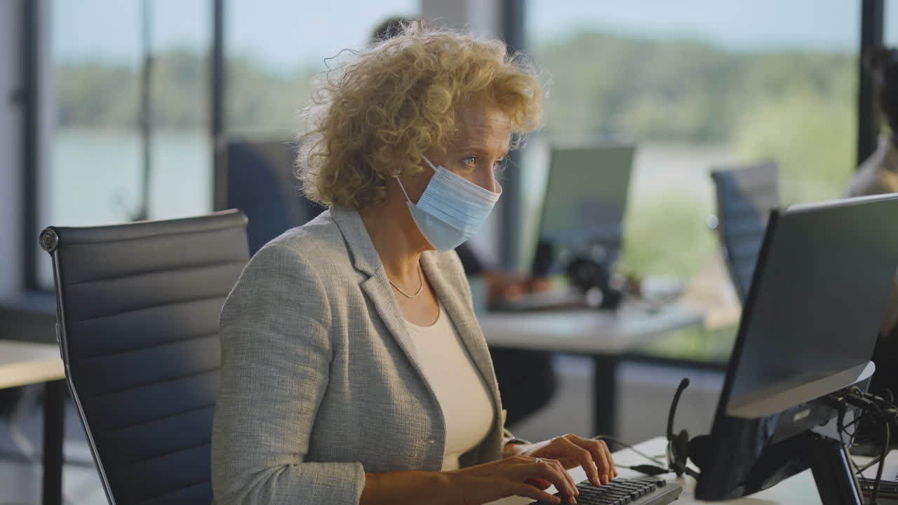 Woman working from home office, wearing face mask