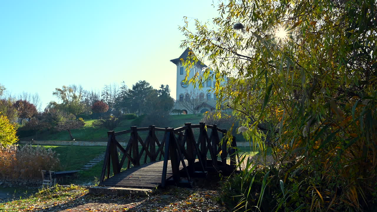 Enjoy a peaceful autumn day in the park featuring a charming wooden bridge and Chateau Purcari surrounded by colorful foliage. Nature is vibrant and inviting