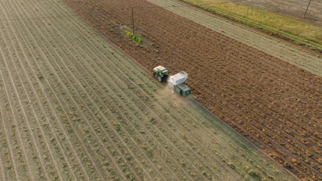 Aerial:-Side-follow-of-a-tractor-plowing-the-soil