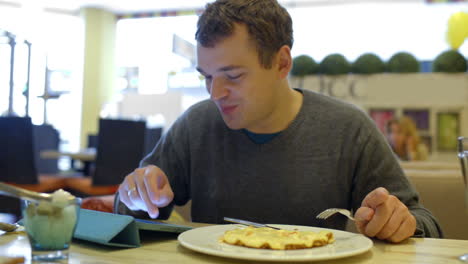 Man-in-cafe-having-dinner-and-using-tablet-PC