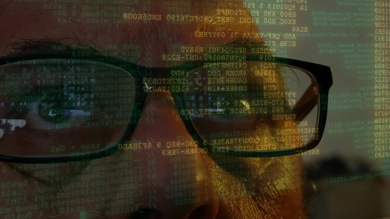 Mand med briller overvåger kodelinjer og datascanning vist foran hans ansigt