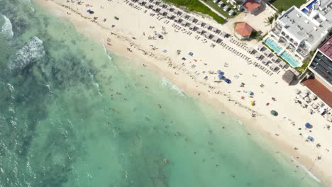 las olas del océano golpean la playa de arena con un lujoso hotel y gente