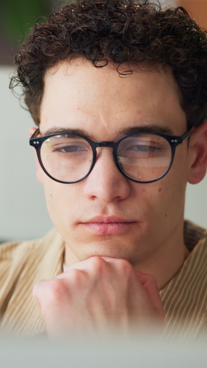 Giovane uomo con gli occhiali concentrato mentre guarda lo schermo