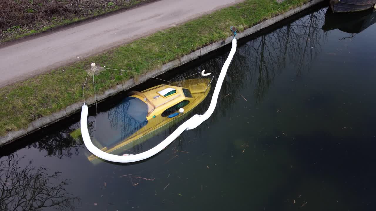 시골길 옆 부두에 정박 중인 침몰한 노란색 쾌속정의 공중 촬영