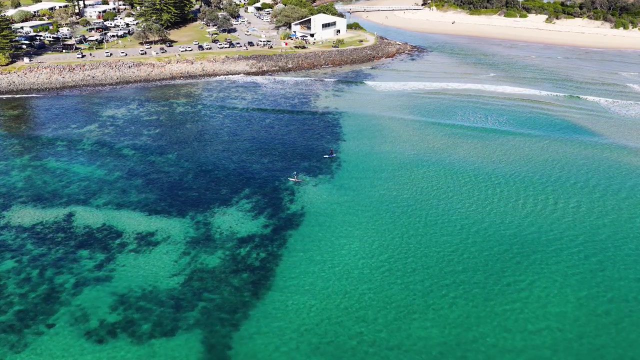 透き通った沿岸の海でパドルボードをする人々の空撮