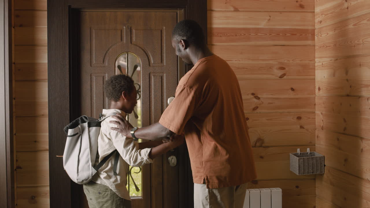 niño golpeando puños con su padre y luego saliendo para ir a la escuela mientras su padre se queda en casa y cierra la puerta