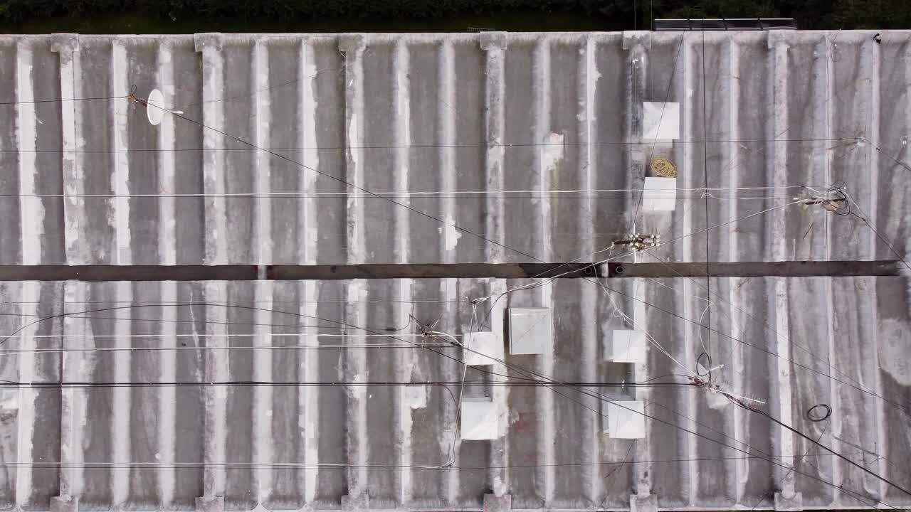 Rooftop with cables and antennas on top of old apartment building, top down
