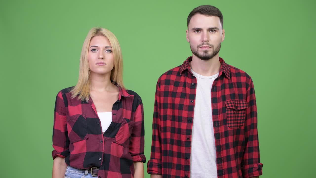 Young couple giving thumbs down and nodding head no together