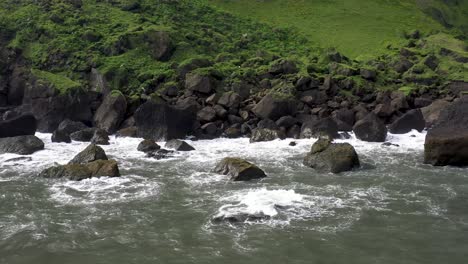 costa en vik, islandia con olas golpeando rocas grandes y negras con video de drones moviéndose hacia los lados