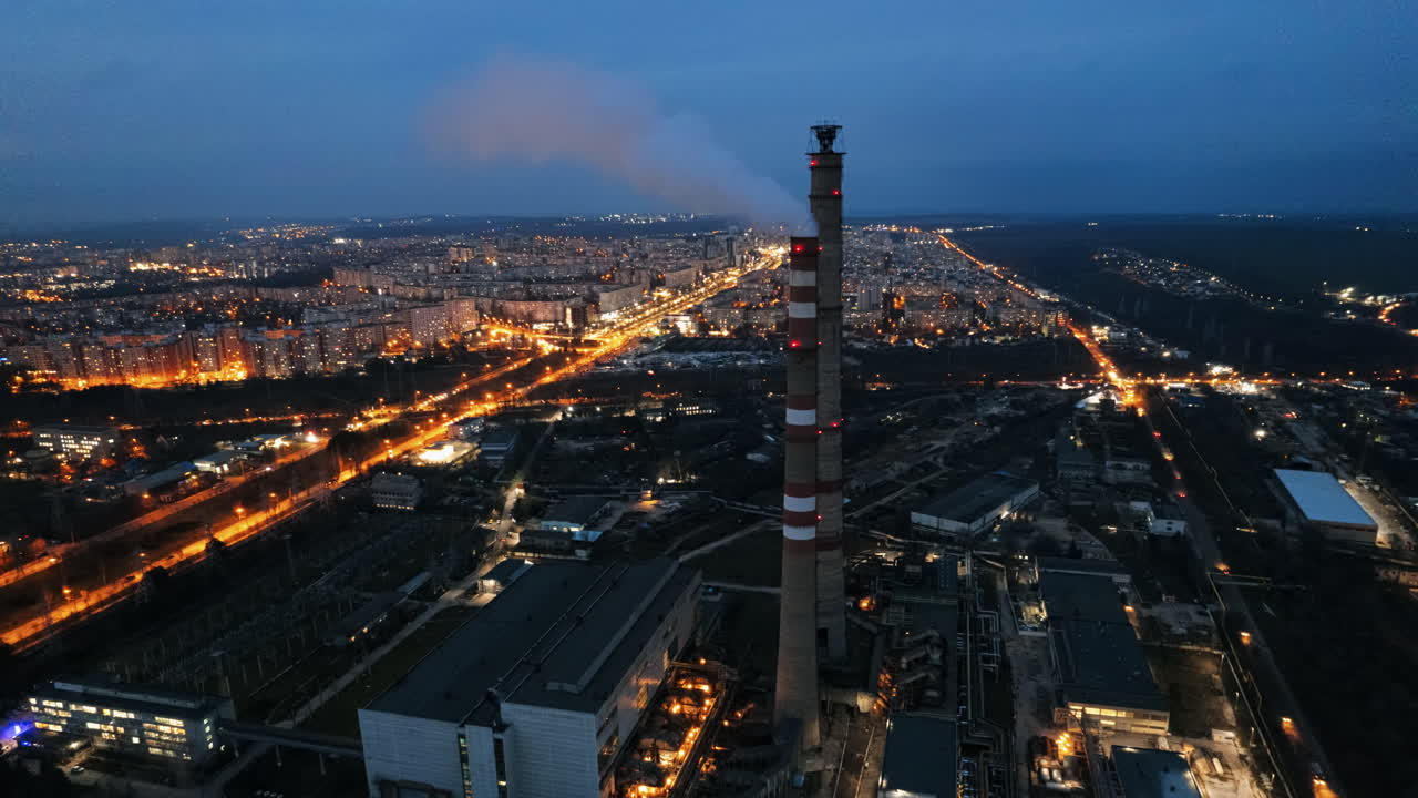 Aerial drone timelapse view of thermal power plant in Chisinau at cloudy weather, Moldova. View of pipes with felling steam, cityscape, illumination, sunset
