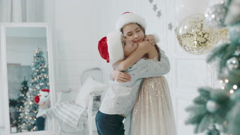 smiling children hugging each other near chritmas tree