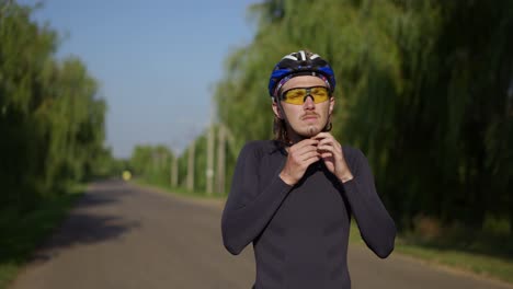 sportsman putting on his helmet and starting riding the bike along the road