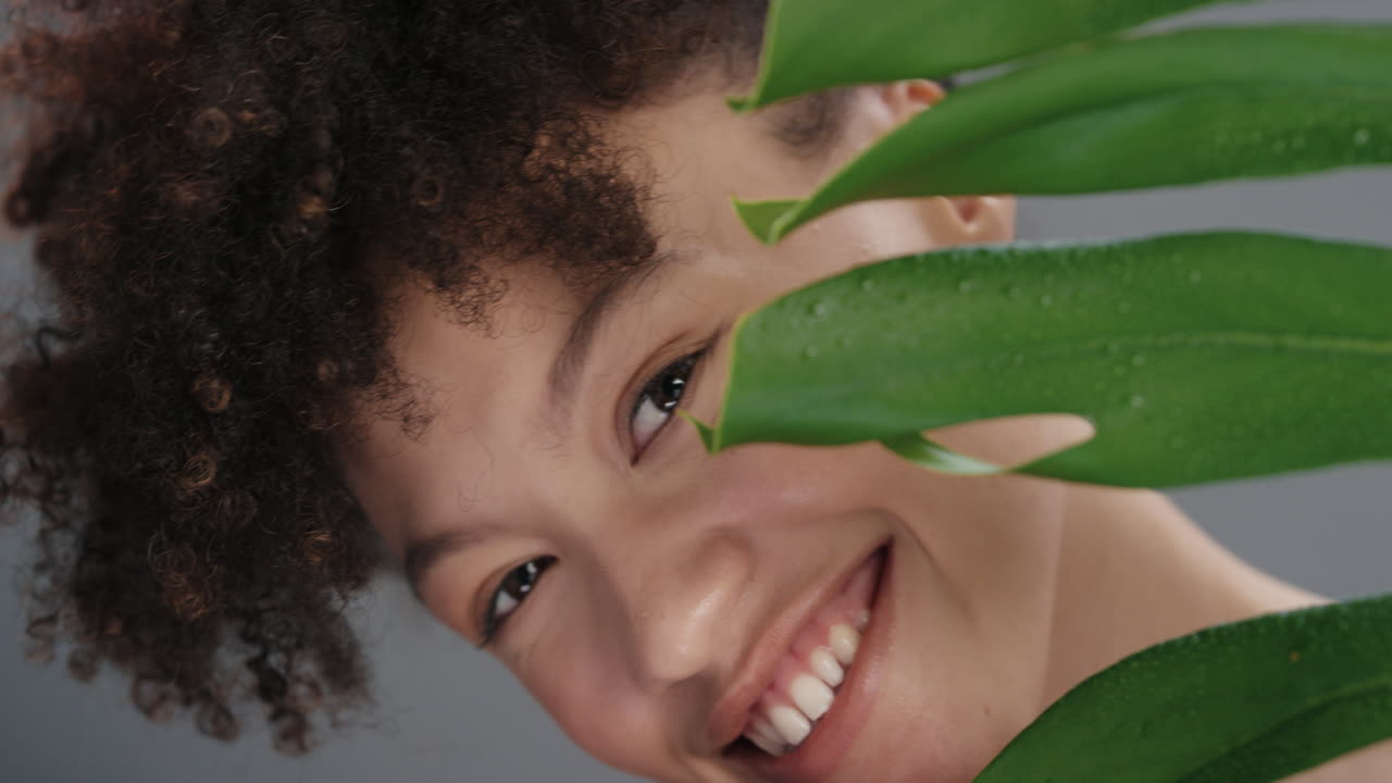 retrato en primer plano de una mujer hermosa que se esconde detrás de las plantas espiando juguetona mujer atractiva con una piel suave y natural que disfruta de un concepto de belleza saludable para el cuidado de la piel