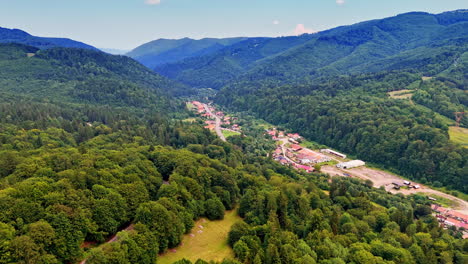 scenic valley view of a peaceful village. lush green hills surround a small village nestled in a valley under a clear blue sky during daylight