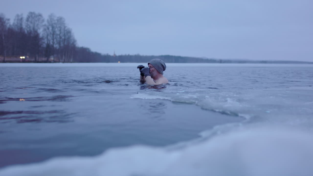 50대 후반의 얼음 목욕하는 남자가 손으로 찍은 사진입니다.