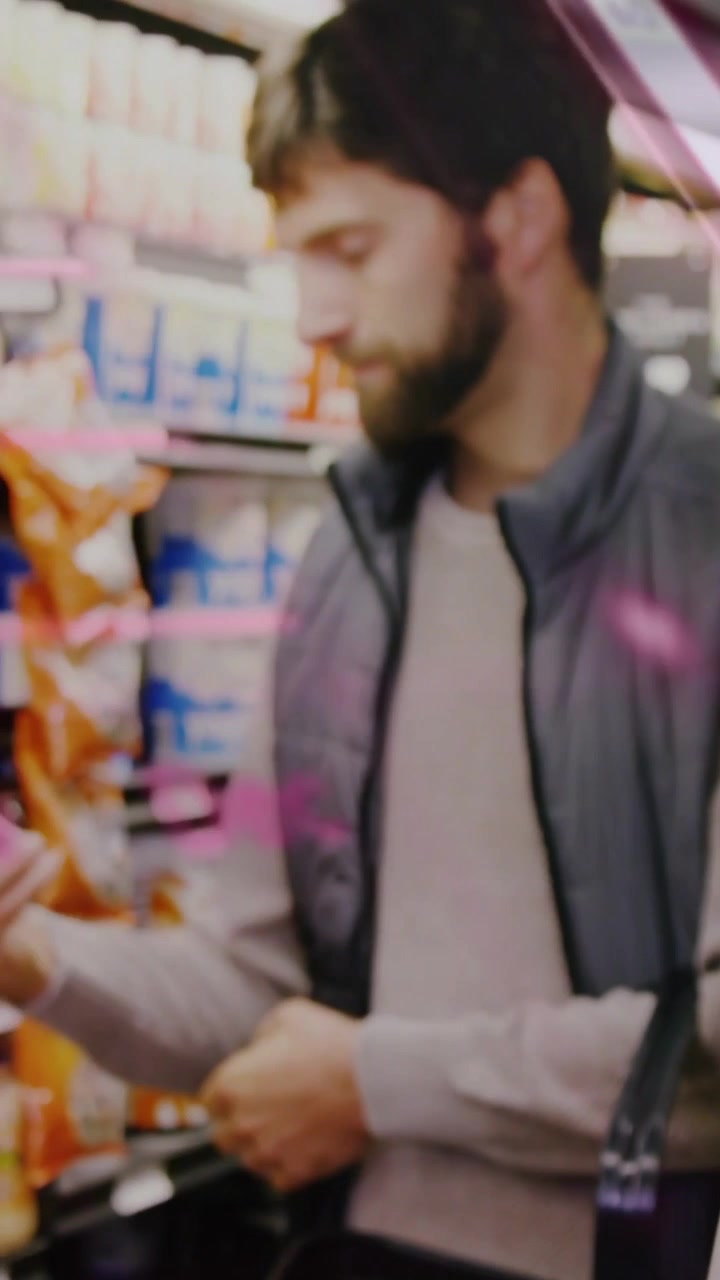 Video verticale: Donna che porge una bottiglia rosa con tappo verde, esortando un uomo che sta leggendo e scegliendo in un negozio, con un filtro rosa.
