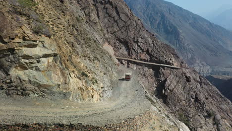 Aerial-shot-of-vehicle-on-Fairy-Meadows-Road-in-Pakistan,-second-deadliest-highway-in-the-world,-roatating-wide-drone-shot