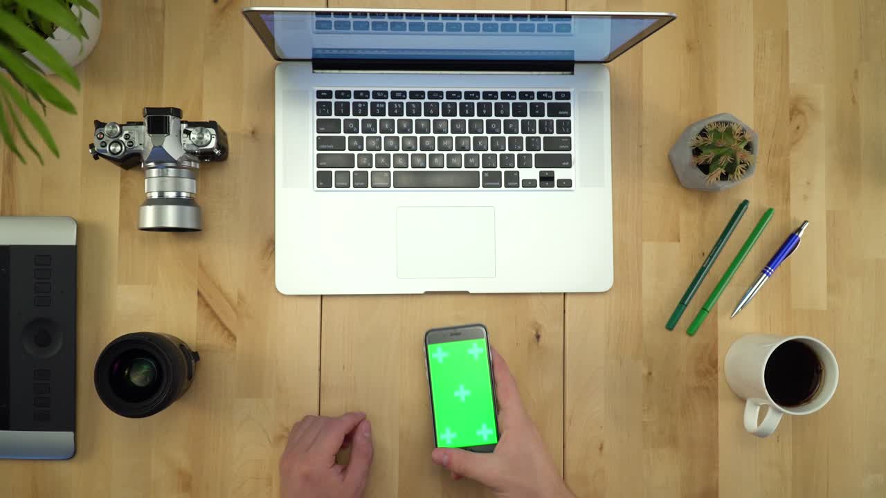 colocación plana de las manos del hombre usando el teléfono con pantalla verde en el lugar de trabajo