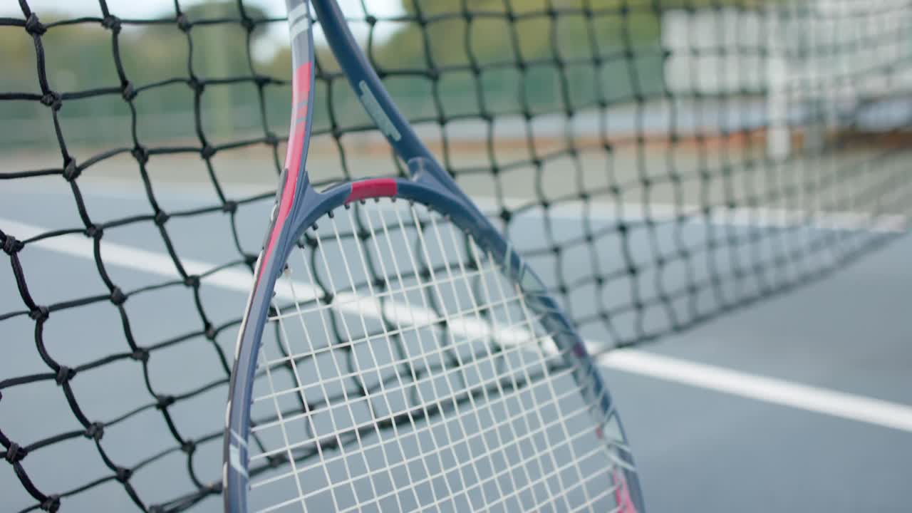 Close up of tennis racket and ball against net at outdoor tennis court, slow motion