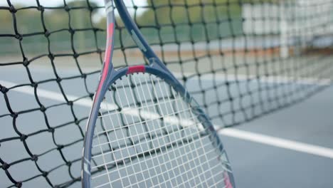 Close-up-of-tennis-racket-and-ball-against-net-at-outdoor-tennis-court,-slow-motion