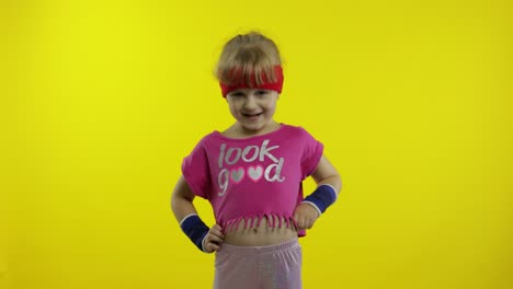 chica atlética en ropa deportiva rosa está agitando la mano haciendo un gesto de saludo en fondo amarillo