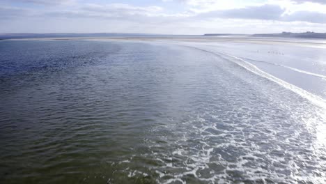 low flying drone shot of the waves breaking at gress beach on a sunny day in the outer hebrides of scotland