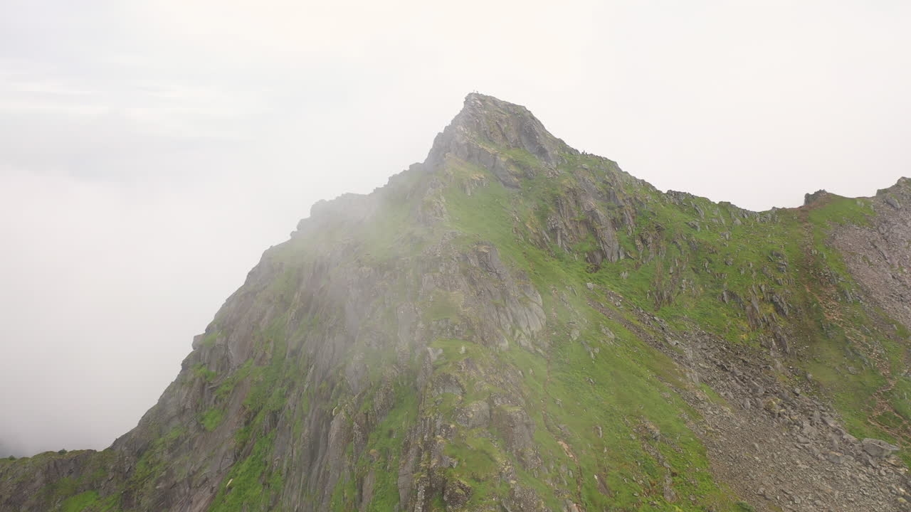 Cinematic rotating drone shot mountain ridge with clouds on one side, Fl&oslash;ya and Djevelporten above Svolv&aelig;r in Lofoten, Norway, aerial footage
