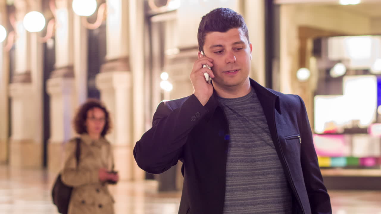 밤에 시내 쇼핑몰에서 전화로 이야기하는 남자