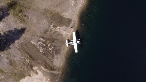 hidroavión amarrado en la orilla del lago desierto, top down dolly fuera