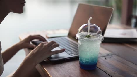 woman working on laptop outside enjoying a refreshing drink