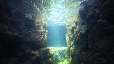 sunlight filters through water in a rocky underwater scene.