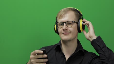 guy listens to music in wireless yellow headphones and dances. chroma key