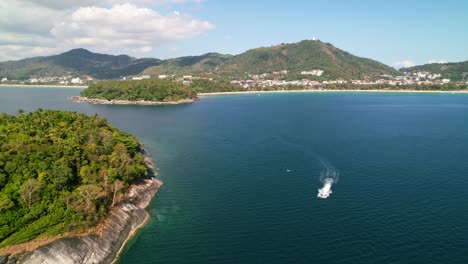 jetski-riding-to-an-island-in-the-middle-of-the-blue-andaman-sea-with-the-white-sand-Karon-beach-coastline-in-the-distance-in-Phuket-Thailand