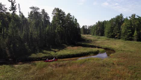 Canoe-traveling-on-narrow-wetland-river,-wilderness-adventure