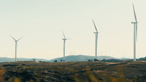 Weite-Aufnahme-Eines-Betriebsbereiten-Feldes-Von-Windrädern-Inmitten-Der-Natürlichen-Schönheit-Der-Berge