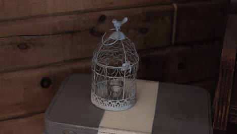 vela de jaula de pájaros sentada en una mesa decorativa con maleta en una recepción de boda